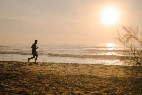 Sahilde koşan siluet adam gün doğumu ve deniz altyapısı ile