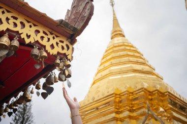 Kadınlar yaz mevsiminde Chiangmai Tayland 'daki tapınakta küçük çanlara dokunur.