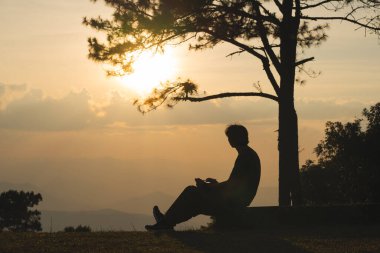 Manzara ve seyahat konsepti yalnız başına çalışan bir adam ve gün batımını ve alacakaranlık gökyüzünü dağ katmanıyla görüyor.