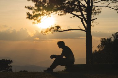 Manzara ve seyahat konsepti yalnız başına çalışan bir adam ve gün batımını ve alacakaranlık gökyüzünü dağ katmanıyla görüyor.