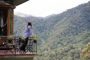 Dijital göçebe konsepti Asyalı serbest çalışan kadın rahatlayıp dağ manzaralı kahve dükkanında çalışıyor.