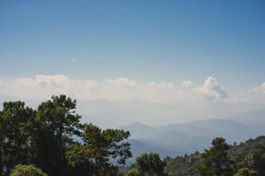 landscape and travel concept with solo freelancer man sit on wooden and use tablet work from outdoor with layer of mountain background