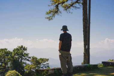 landscape and travel concept with solo freelancer man sit on wooden and use tablet work from outdoor with layer of mountain background