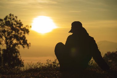 peyzaj ve seyahat konsepti yalnız başına çalışan bir adam yerde oturur ve dağ zemininde güneşin doğuşunu seyreder.