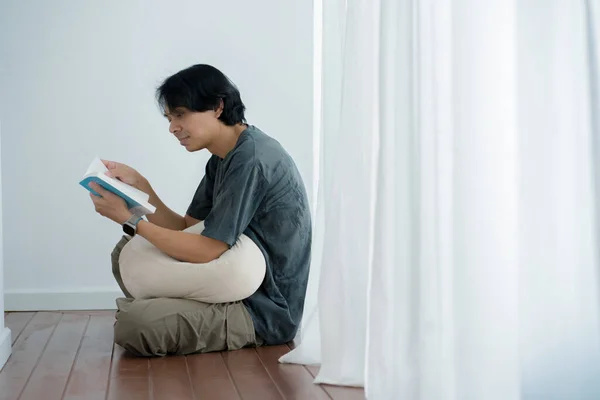 wellness and wellbeing concept with asian man sit and relax and read in livingroom