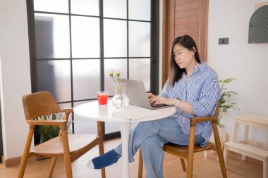 Asyalı kadın serbest yazar, evde çalışırken rahat ve mutlu.