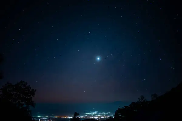 seyahat ve insan etkinliği gece yıldızlı konsept dağda ağaçlı ve şehrin arka planında ışıklandırma