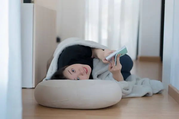 wellness and wellbeing concept with asian woman lie down and read book in livingroom