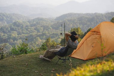 Manzara ve seyahat konsepti yalnız başına çalışan bir adam rahatlar ve dağ tabakasıyla gün batımını ve alacakaranlık gökyüzünü seyreder.