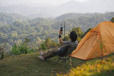 Manzara ve seyahat konsepti yalnız başına çalışan bir adam rahatlar ve dağ tabakasıyla gün batımını ve alacakaranlık gökyüzünü seyreder.