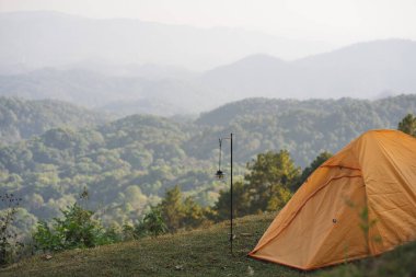 Turuncu kamp çadırı ve dağ katmanlı manzara ve seyahat kavramı