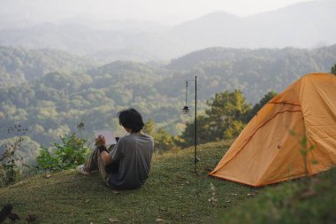 peyzaj ve seyahat konsepti yalnız başına çalışan bir adam tablet kullanır ve kedi ile oynar ve dağ katmanını görür.