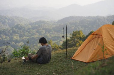 peyzaj ve seyahat konsepti yalnız başına çalışan bir adam tablet kullanır ve kedi ile oynar ve dağ katmanını görür.