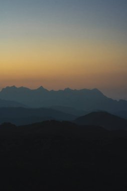 Doğa turuncu gökyüzü ve gün doğumuyla birlikte dağ katmanıyla seyahat ediyor.