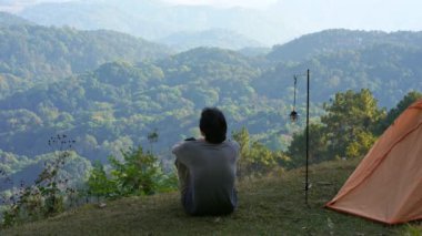 peyzaj ve seyahat konsepti yalnız başına kamp yapan ve açık havada çalışan bir adam ve dağ arka planının katmanını görüyor