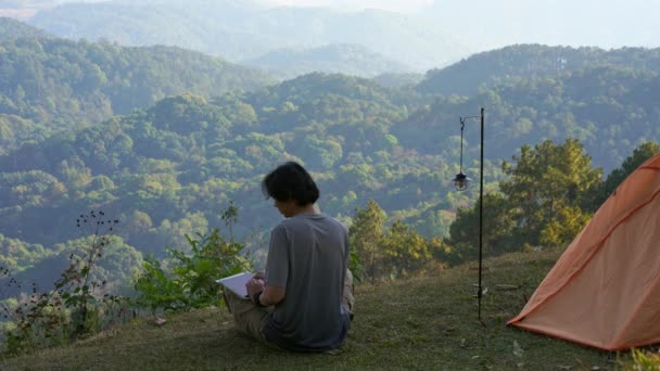 ソロフリーランサーの男性キャンプの仕事と山の背景の層でリラックスした風景と旅行コンセプト — ストック動画