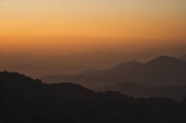 Doğa turuncu gökyüzü ve gün doğumuyla birlikte dağ katmanıyla seyahat ediyor.