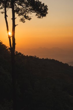 Doğa turuncu gökyüzü ve gün doğumuyla birlikte dağ katmanıyla seyahat ediyor.