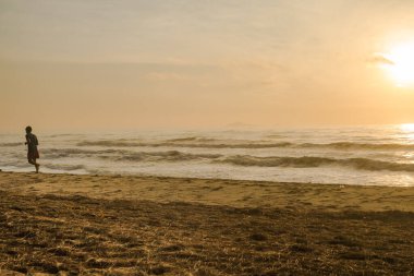 Sahilde koşan siluet adam gün doğumu ve deniz altyapısı ile