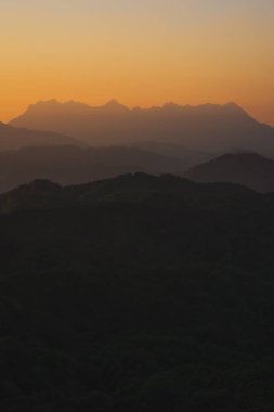 Doğa turuncu gökyüzü ve gün doğumuyla birlikte dağ katmanıyla seyahat ediyor.