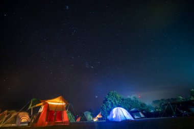 Gece yıldızlı kamp çadırlı seyahat ve insan aktiviteleri konsepti.