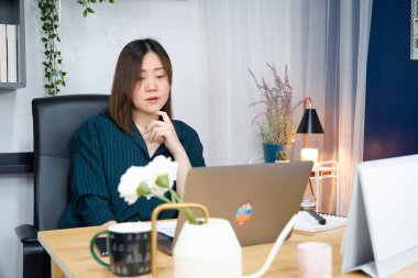 Asyalı kadın işini evden yürütmek için dizüstü bilgisayar kullanıyor.