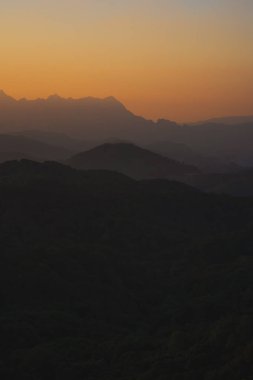 Doğa turuncu gökyüzü ve gün doğumuyla birlikte dağ katmanıyla seyahat ediyor.