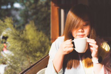 Modern bir otelde sabah kahvaltısıyla birlikte sıcak çay ve kahve içen Asyalı bir kadın.