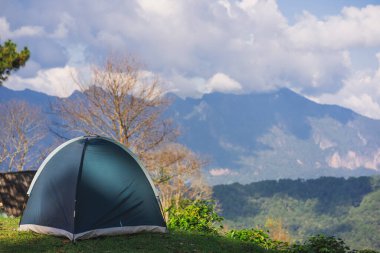 Güneş ışığıyla manzara ve seyahat kavramı ve dağda kamp çadırıyla bulutlu gökyüzü