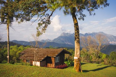 Güneş ışığıyla manzara ve seyahat kavramı ve bulutlu gökyüzü ve dağdaki kır evi.