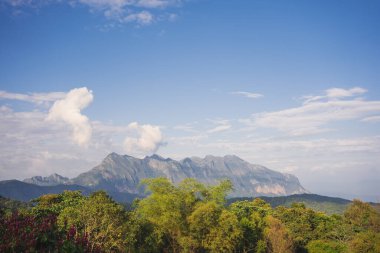 Güneş ışığı ve dağlı bulutlu gökyüzü ile manzara ve seyahat kavramı