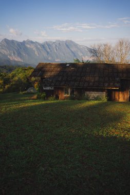 Güneş ışığıyla manzara ve seyahat kavramı ve bulutlu gökyüzü ve dağdaki kır evi.