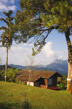 Güneş ışığıyla manzara ve seyahat kavramı ve bulutlu gökyüzü ve dağdaki kır evi.