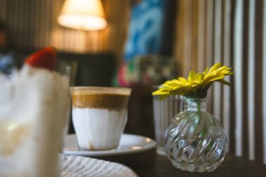 Kahve dükkanındaki ahşap masada kahve ve pastayla mutlu ve neşeli.