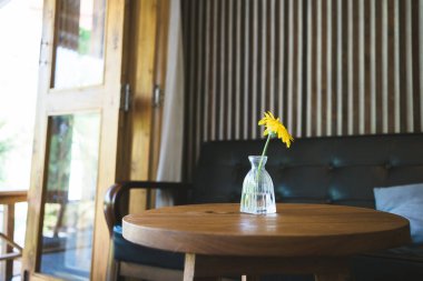 Kahve dükkanındaki ahşap masaya çiçek süsleyerek mutlu ve neşeli.