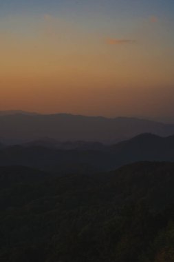 Doğa turuncu gökyüzü ve gün doğumuyla birlikte dağ katmanıyla seyahat ediyor.