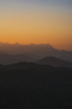 Doğa turuncu gökyüzü ve gün doğumuyla birlikte dağ katmanıyla seyahat ediyor.