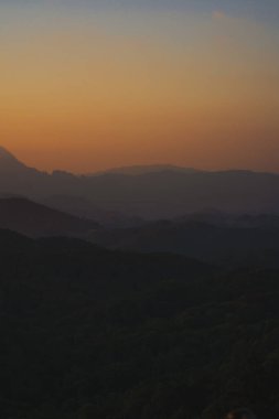 Doğa turuncu gökyüzü ve gün doğumuyla birlikte dağ katmanıyla seyahat ediyor.
