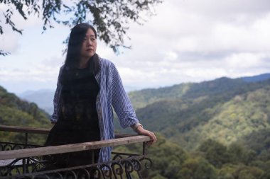 Dijital göçebe konsepti Asyalı serbest çalışan kadın rahatlayıp dağ manzaralı kahve dükkanında çalışıyor.