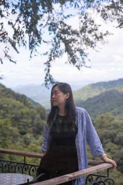 Dijital göçebe konsepti Asyalı serbest çalışan kadın rahatlayıp dağ manzaralı kahve dükkanında çalışıyor.