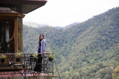 Dijital göçebe konsepti Asyalı serbest çalışan kadın rahatlayıp dağ manzaralı kahve dükkanında çalışıyor.