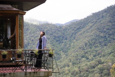 Dijital göçebe konsepti Asyalı serbest çalışan kadın rahatlayıp dağ manzaralı kahve dükkanında çalışıyor.