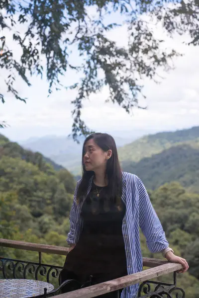 Dijital göçebe konsepti Asyalı serbest çalışan kadın rahatlayıp dağ manzaralı kahve dükkanında çalışıyor.