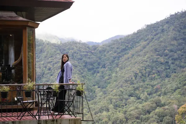 Dijital göçebe konsepti Asyalı serbest çalışan kadın rahatlayıp dağ manzaralı kahve dükkanında çalışıyor.