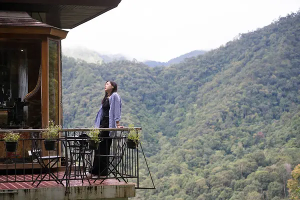 Dijital göçebe konsepti Asyalı serbest çalışan kadın rahatlayıp dağ manzaralı kahve dükkanında çalışıyor.