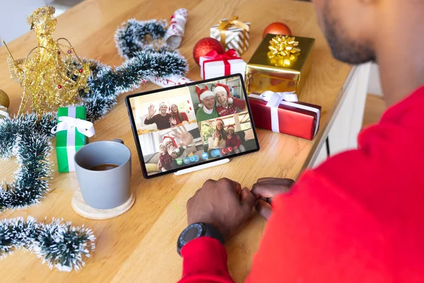 アフリカ系アメリカ人の男性は様々な人とクリスマスビデオ通話をしています 通信技術とクリスマス デジタル複合画像 — ストック写真