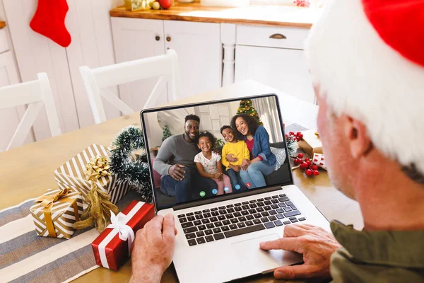 Senior caucasian man having christmas video call with african american family. Communication technology and christmas, digital composite image.