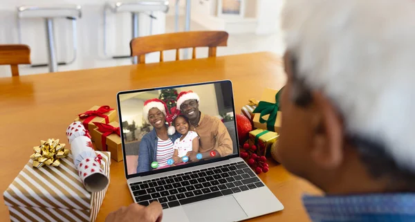 Senior biracial man having christmas video call with african american family. Communication technology and christmas, digital composite image.