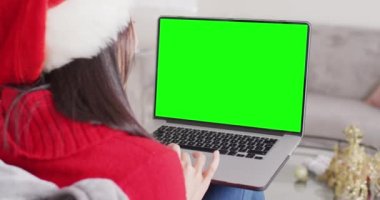 Asyalı kadın bilgisayarını kopyalama alanı ile görüntülü görüşme için kullanıyor. İletişim teknolojisi ve noel, dijital kompozit video.