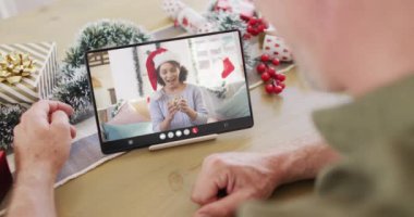 Kafkasyalı bir adam, Noel süslemeleri ile melez bir kadınla tablet video görüşmesi yapıyor. Noel, kutlama, dijital kompozit video.